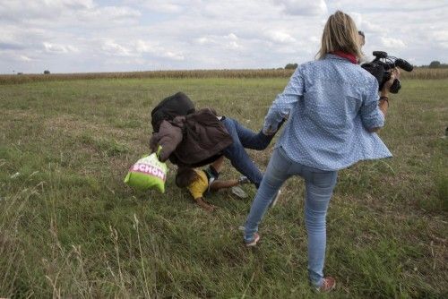 Una reportera húngara agrede a un refugiado que carga con su hijo.