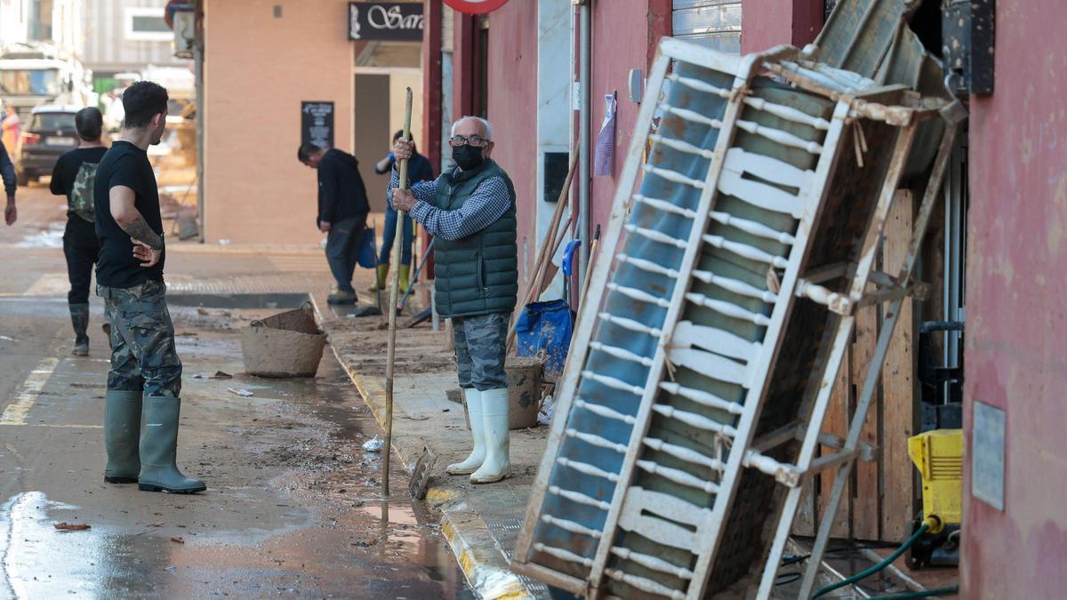 Un vecino de Massanassa trata de desatascar una alcantarilla.