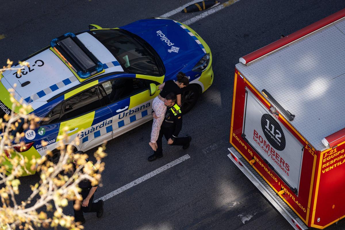 Un bombero de Barcelona traslada a una mujer durante la extinción del incendio de un piso en la calle Urgell