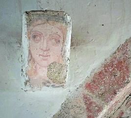 Canecillo de la cabeza de una mujer en el paramento izquierdo del arco central en Torrefrades.