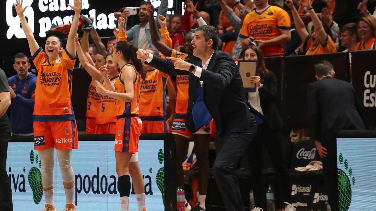El entrenador del Valencia Basket, Rubén Burgos, no deja de dar instrucciones en los instantes finales, mientras la afición y las jugadoras festejan la clasificación