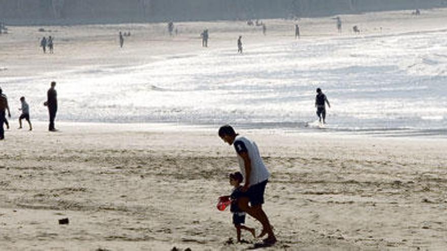 La playa de Salinas, ayer, con los primeros bañistas y paseantes de la primavera.