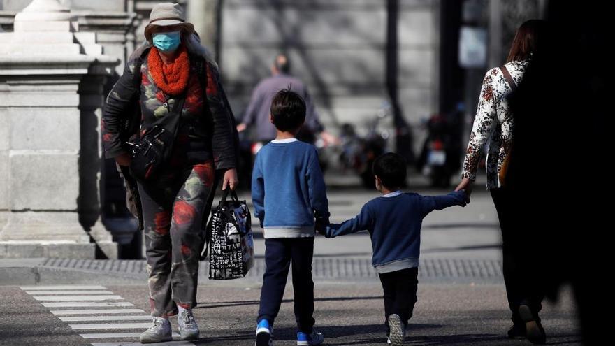 Una mujer con mascarilla junto a dos niños en Madrid.