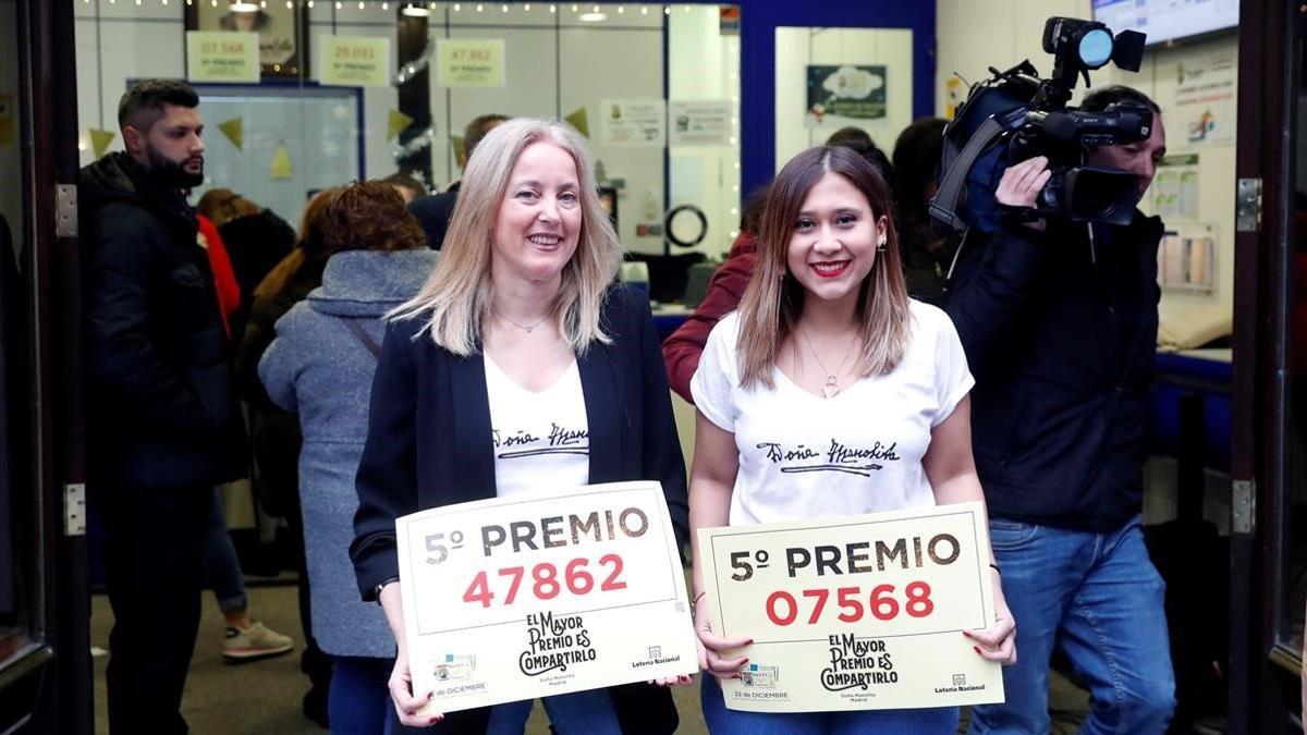 Dos empleadas de la administración de calle Carmen 22, en Madrid, muestran dos quintos premios del sorteo.