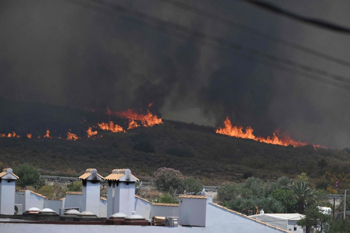 Una foto tomada el 10 de julio de 2026 muestra llamas con casas en primer plano, en el área de un incendio forestal que mató a 11 personas cerca de Bedar, en el distrito de Los Gallardos, en la provincia de Almería.