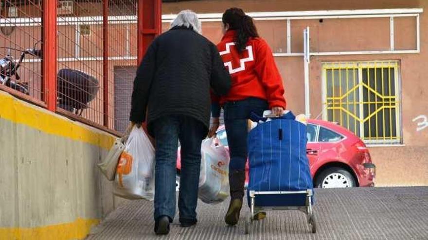 Una voluntaria ayuda a una mujer mayor a llevar los alimentos a casa.