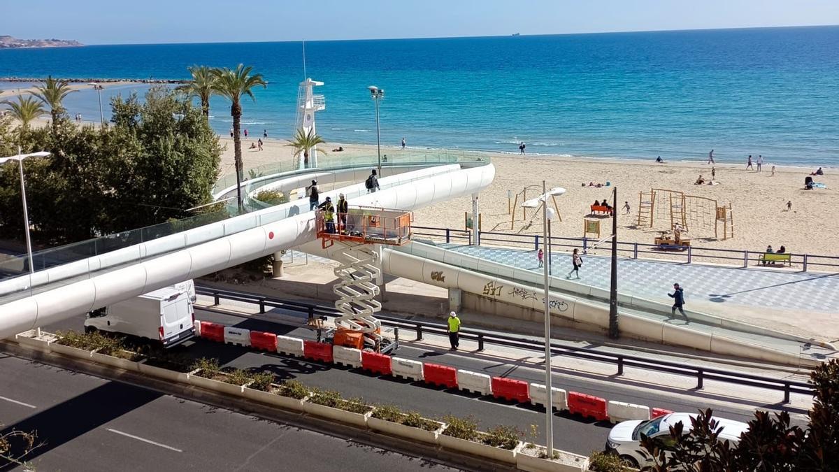 Unos obreros repaean el &quot;agujero&quot; en la pasarela del Postiguet.