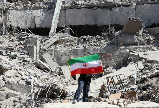 Un iraní coloca la bandera nacional de Irán entre las ruinas de una comisaría de policía dañada en el centro de Teherán, Irán, el pasado 4 de marzo de 2026