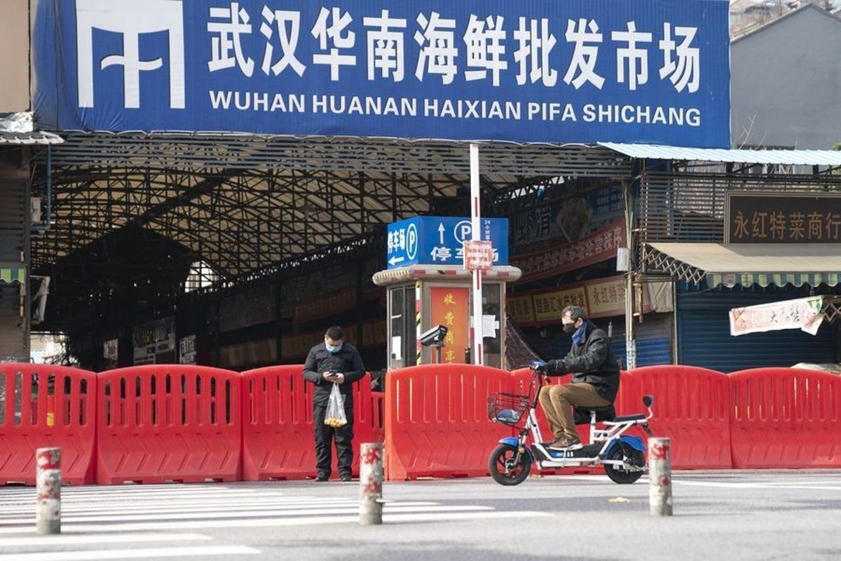 Dos ciudadanos pasan por la entrada del mercado de mariscos Huanan en Wuhan.
