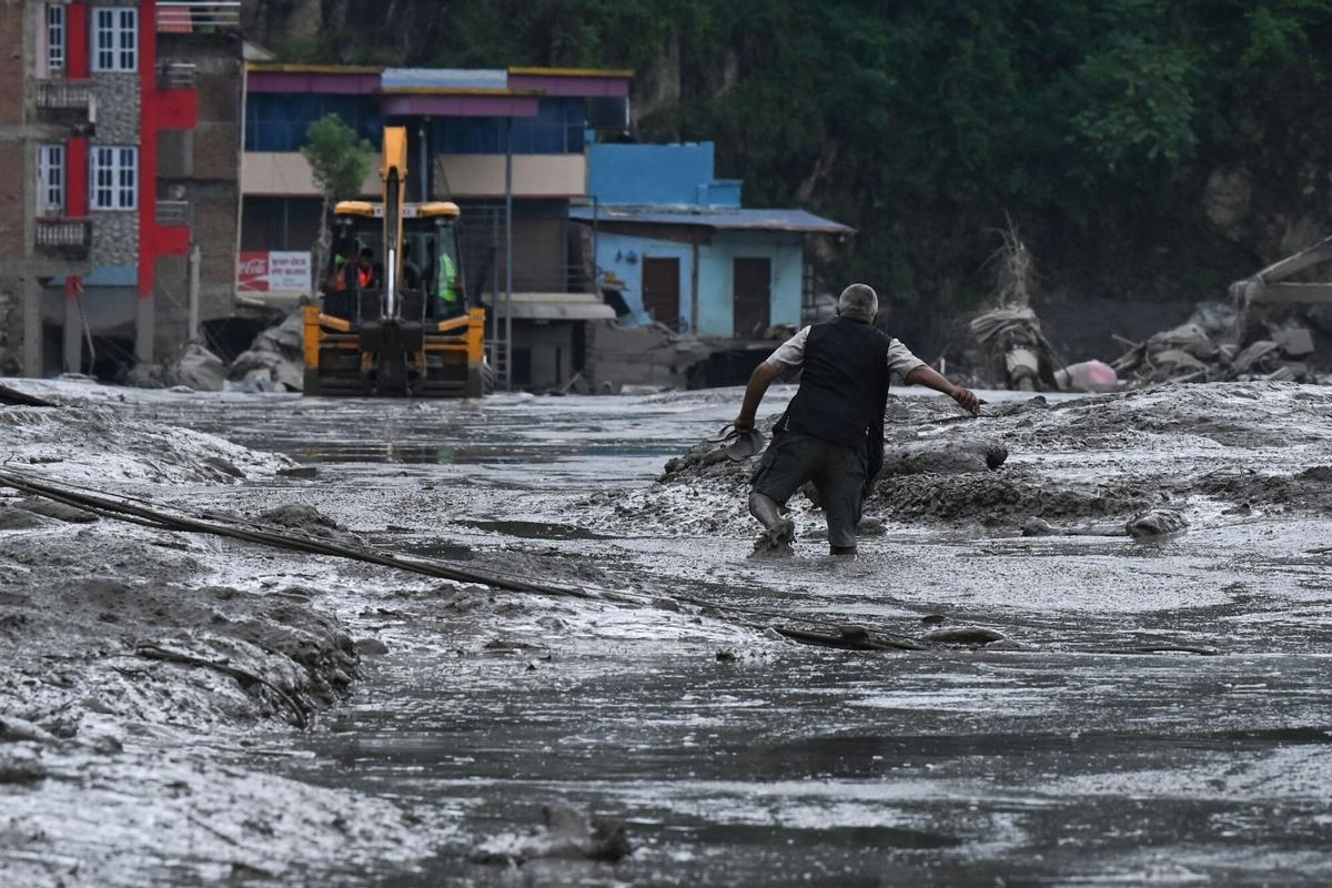 A resident walks along a street covered in mud following flash floods and a landslide disaster in Devighat, in Nepals Nuwakot district on August 26, 2026. Rescue teams rushed on August 27 to find hundreds of people missing on the Nepal-Tibet border in flash floods and landslides that killed at least 160 and swept away entire villages. (Photo by PRAKASH MATHEMA / AFP). ALTERNATIVE RECROP