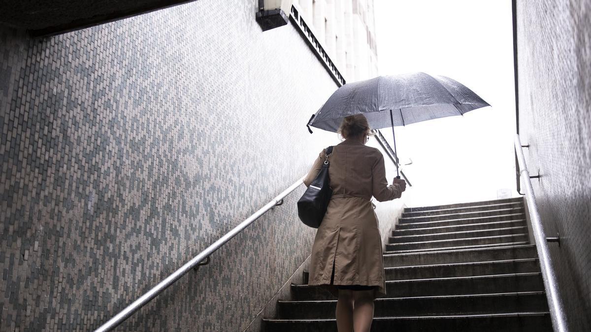 Una mujer saliendo del transporte público en un día de lluvia.