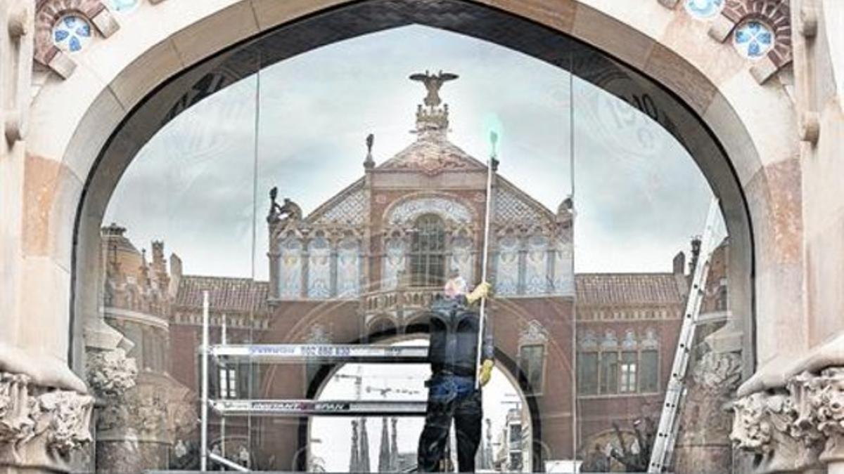 Un operario limpia los cristales de la entrada principal del recinto modernista de Sant Pau, ayer.