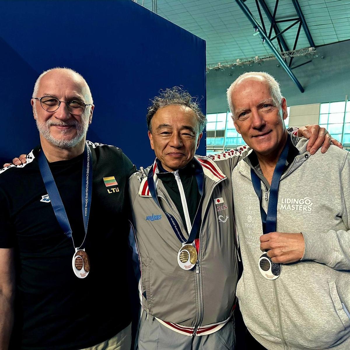 Eric con los nadadores japones y lituano, que coparon los podiums en el Mundial de Natación de Doha.