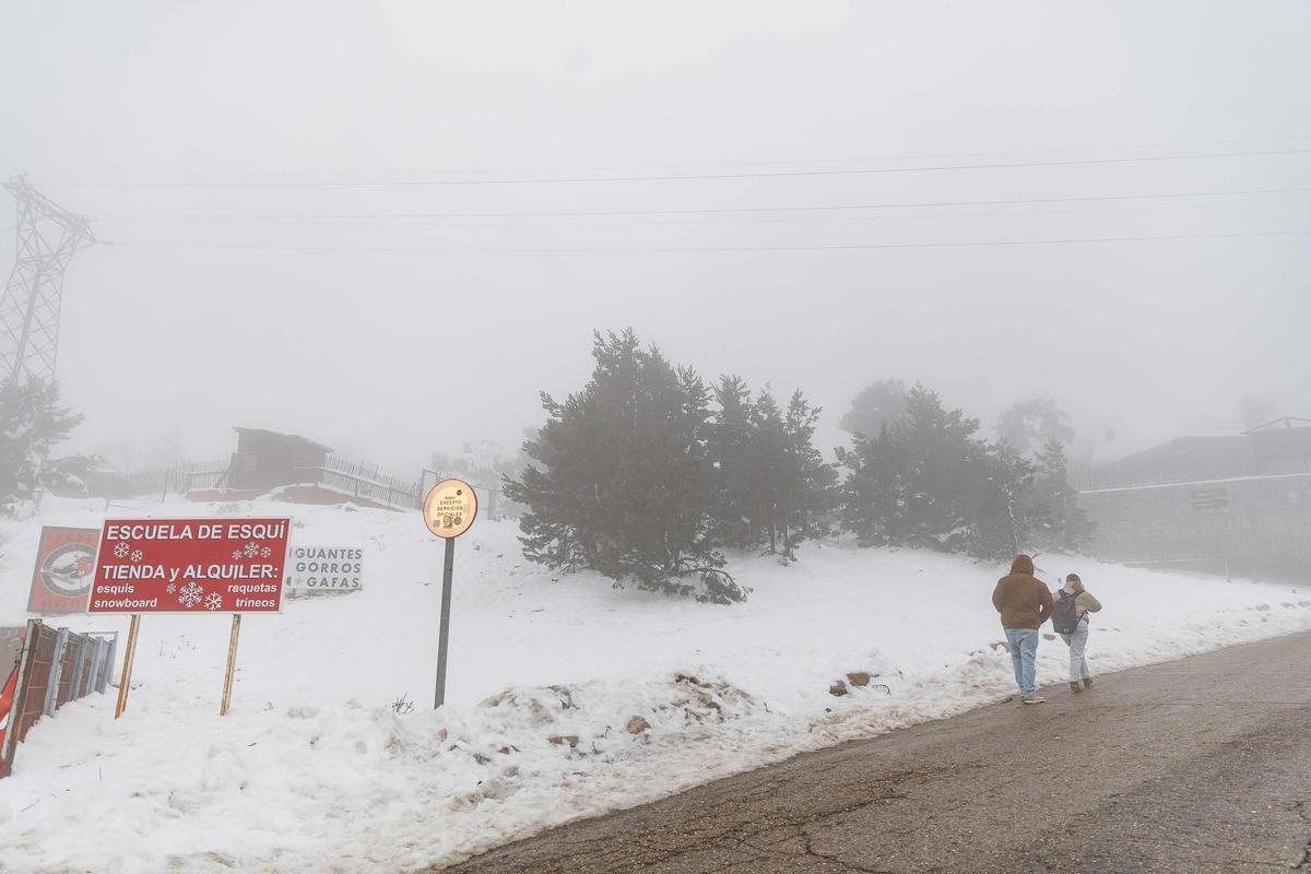 Dos personas caminan por una pista forestal en el Puerto de Navacerrada, en Cercedilla.