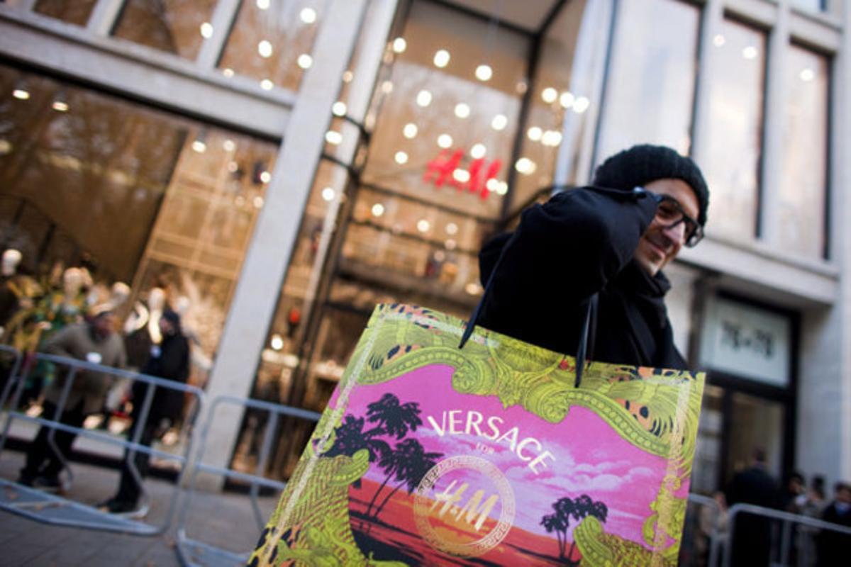 Un home mostra la bossa al sortir d’una botiga HM després del llançament de la col·lecció de Versace per a HM.