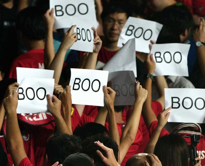 Las personas dan la espalda y abuchean mientras sostienen pancartas durante el himno chino al comienzo del partido de fútbol clasificatorio para la Copa Mundial 2022 de Qatar entre Irán y Hong Kong en el Estadio de Hong Kong.