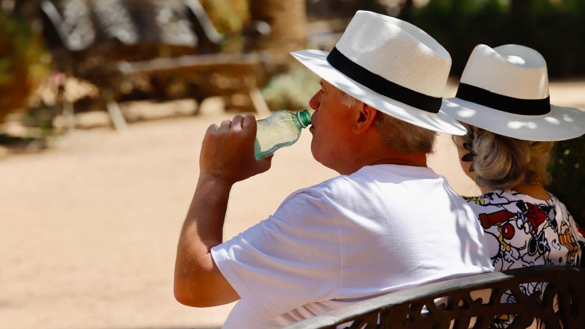 Una pareja se protege del sol con sombreros y bebe agua en Córdoba.