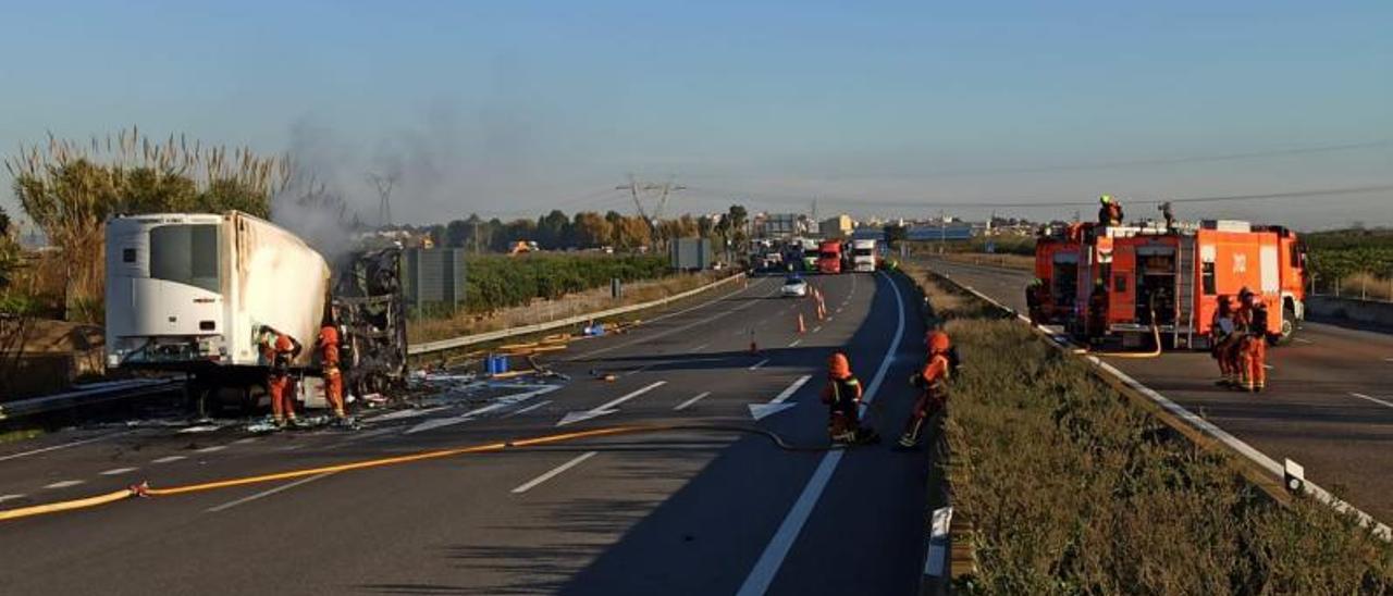 Los bomberos apagando el fuego del remolque accidentado en la A-7. | LEVANTE-EMV