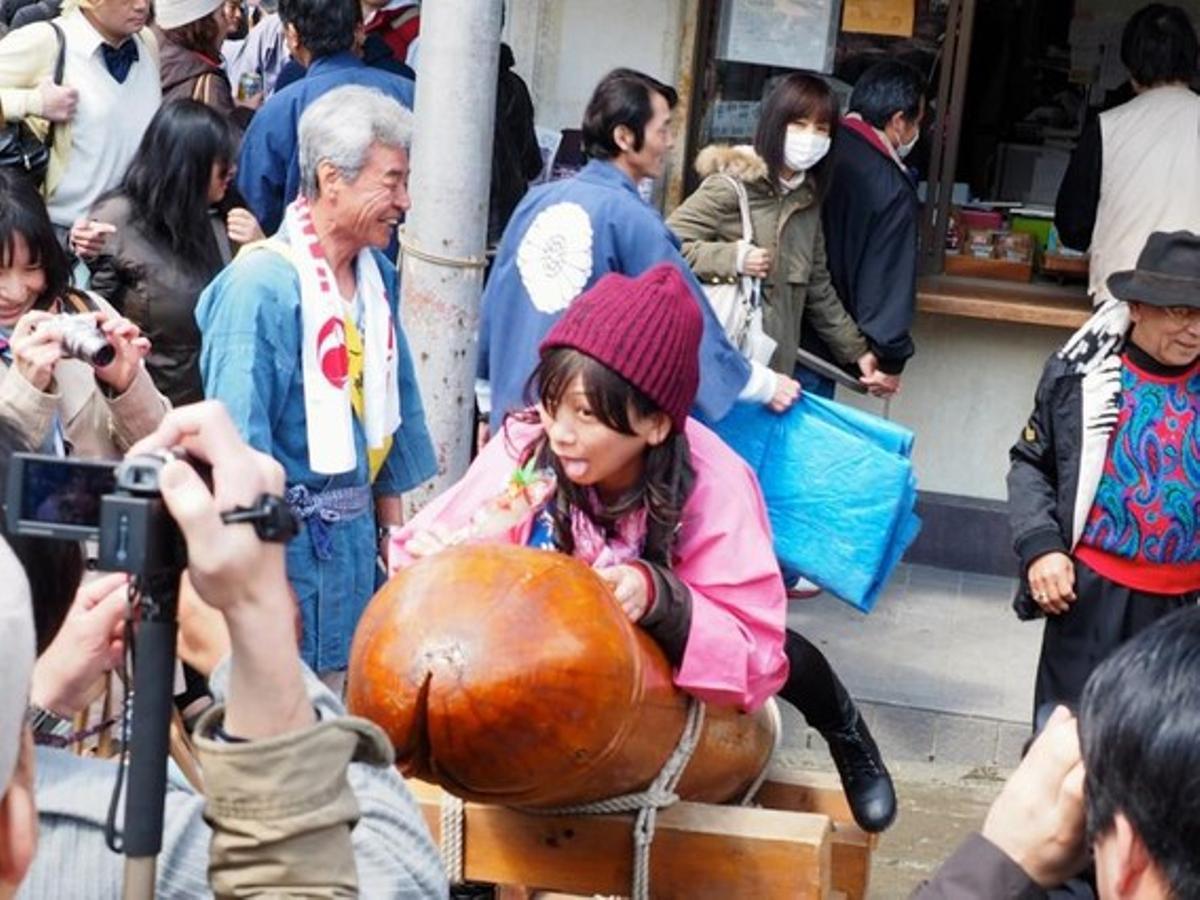Una noia s’ajeu sobre la figura d’un penis durant el Kanamara Matsuri, al Japó.