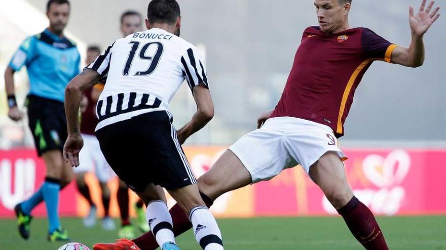 Dzeko, del Roma, a la izquierda, toca ante Bonucci.