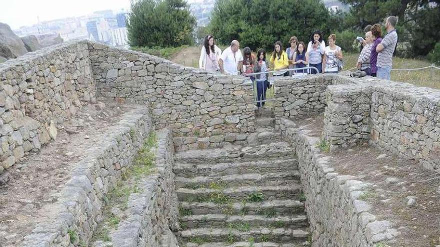 Un grupo de visitantes, ante el aljibe del castro de Elviña.