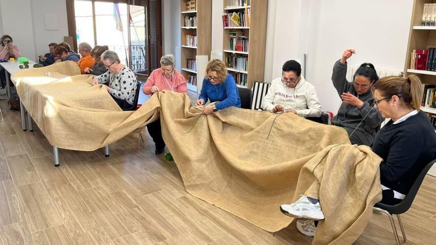 Participantes en el taller de crochet decoran las telas con las que han creado los murales de la exposición. |