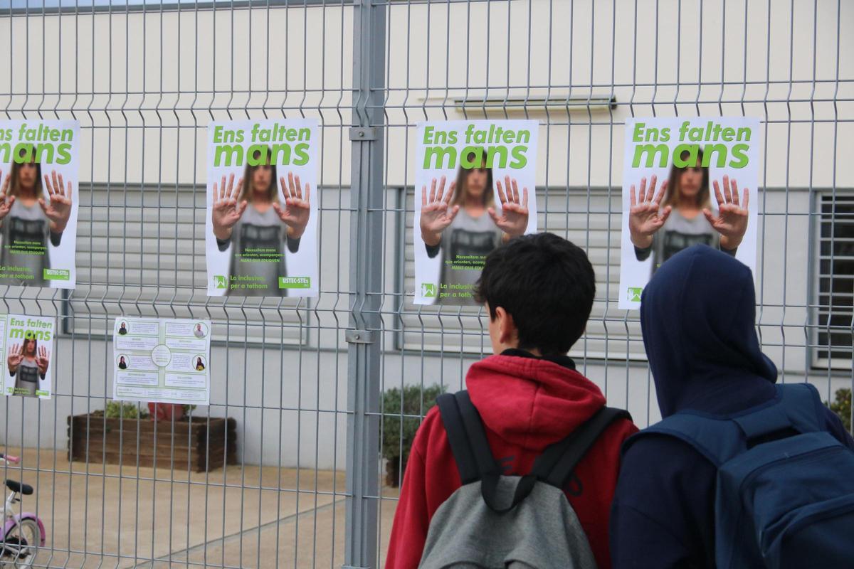 Dos nens miren els cartells de la campanya d'USTEC a l'escola Esculapi de l'Escala.