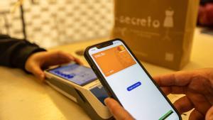 Nuevos sistemas de pago en un comercio de proximidad, un cliente paga con targeta