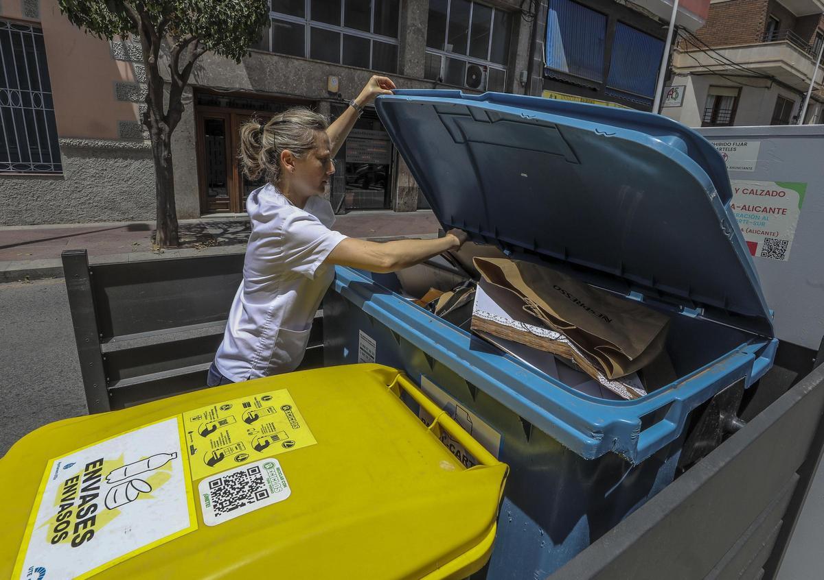 Una ciudadana deposita cartón en un contenedor en Elche