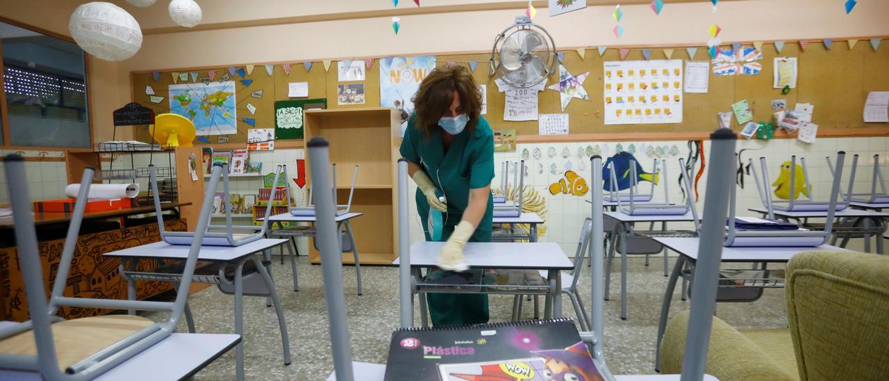 Una limpiadora desinfecta un aula.