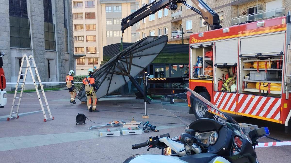 Los bomberos y la policía con el &quot;paraguas&quot; que fue derribado por el camión.