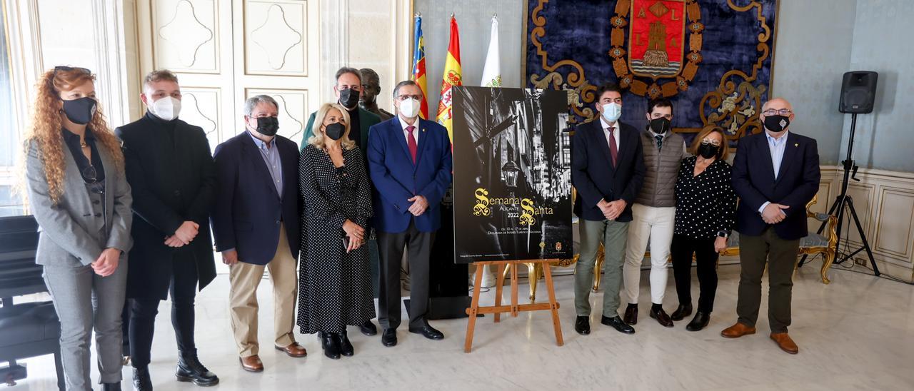 Foto de familia junto al cartel anunciador de la Semana Santa, cuyo diseño de ha promovido desde la propia Junta