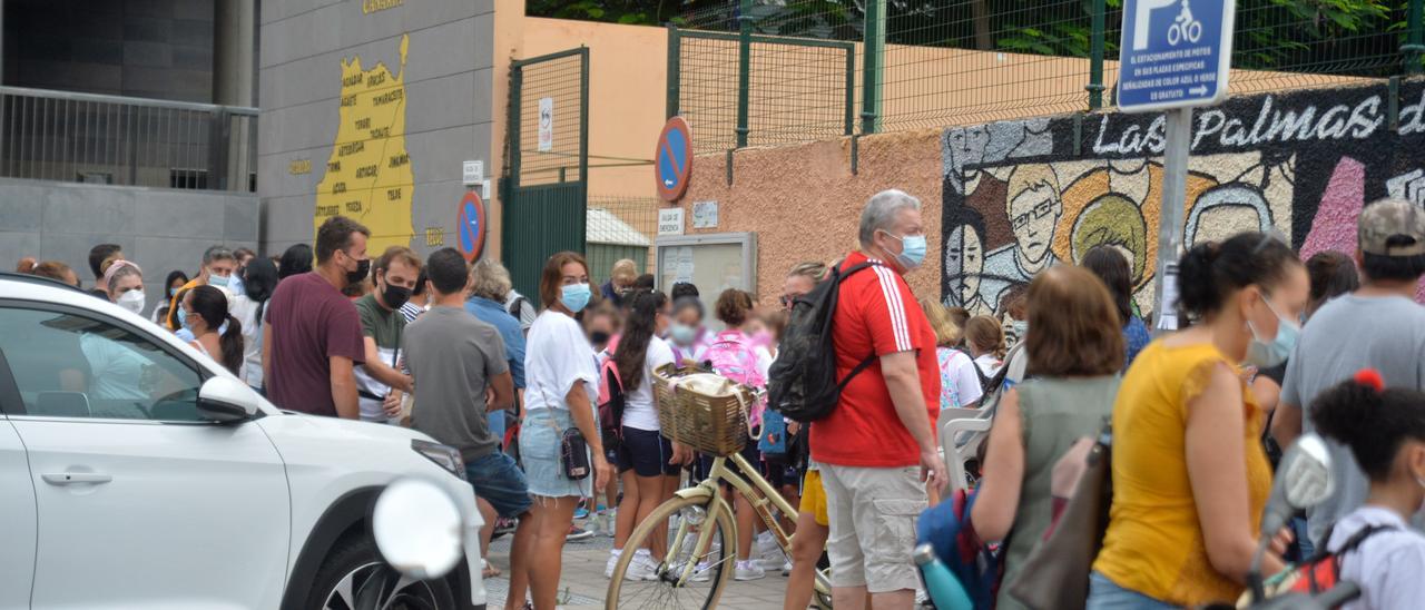 Alumnos y progenitores con mascarilla en el acceso a un centro educativo