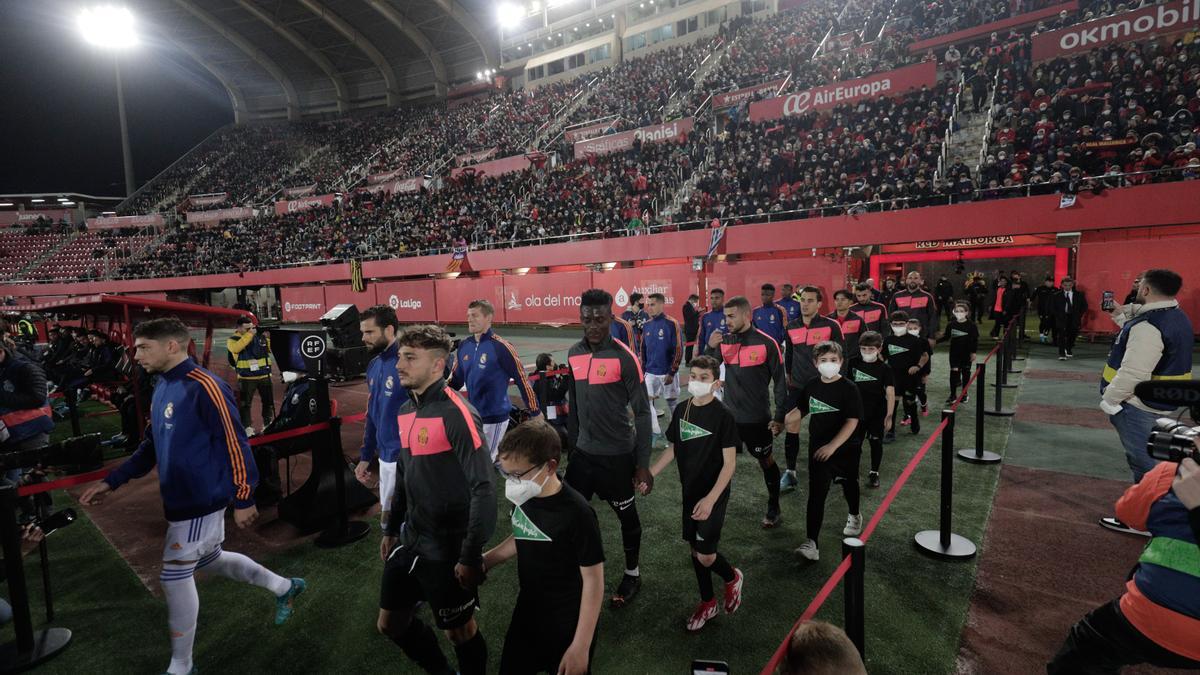 El Mallorca y el Real Madrid entran al terreno de juego en el partido de la pasada temporada, con la tribuna cubierta llena.