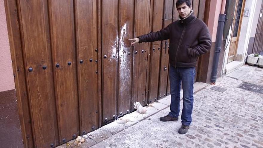 El dueño del local muestra el aspecto que presentaba ayer por la mañana la puerta de acceso tras el ataque.