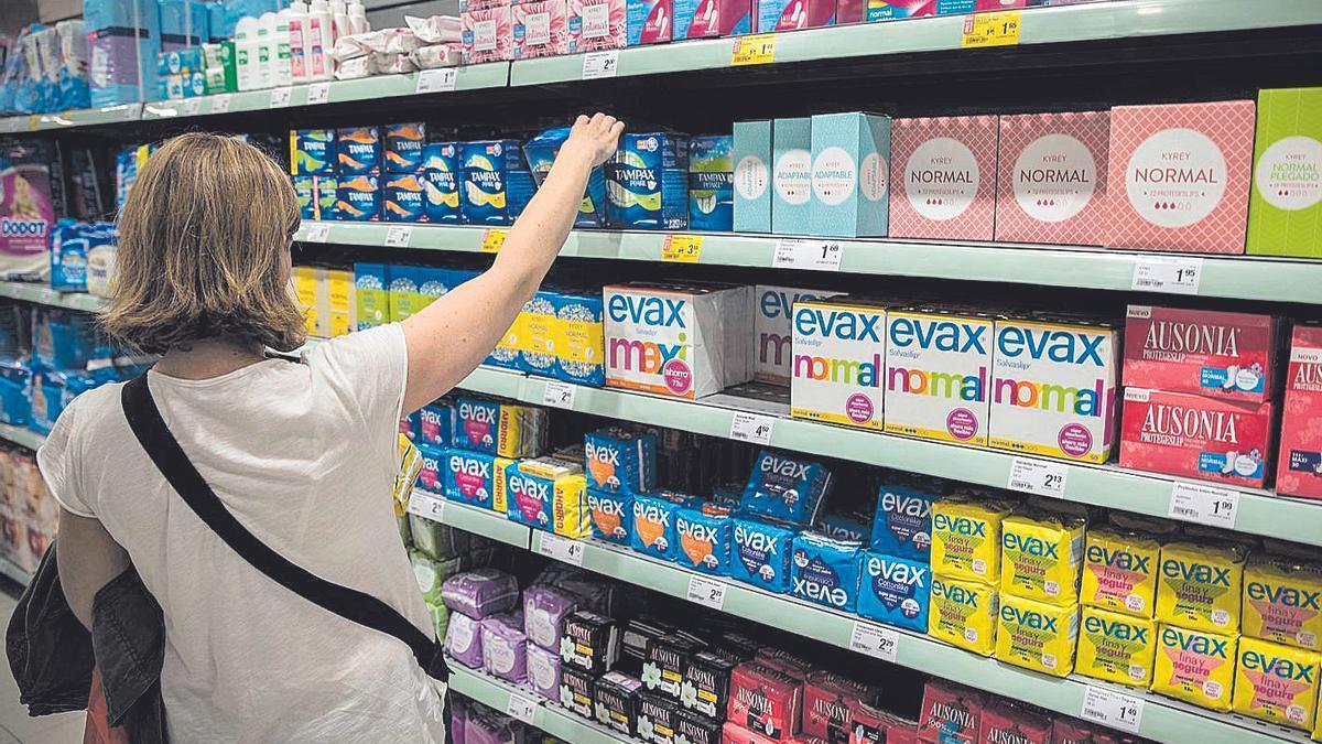 Una mujer escoge productos menstruales en un supermercado