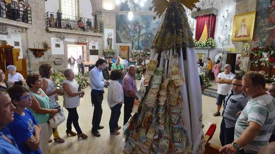 El manto de la Virgen colmado de billetes de donativos. // G. S.