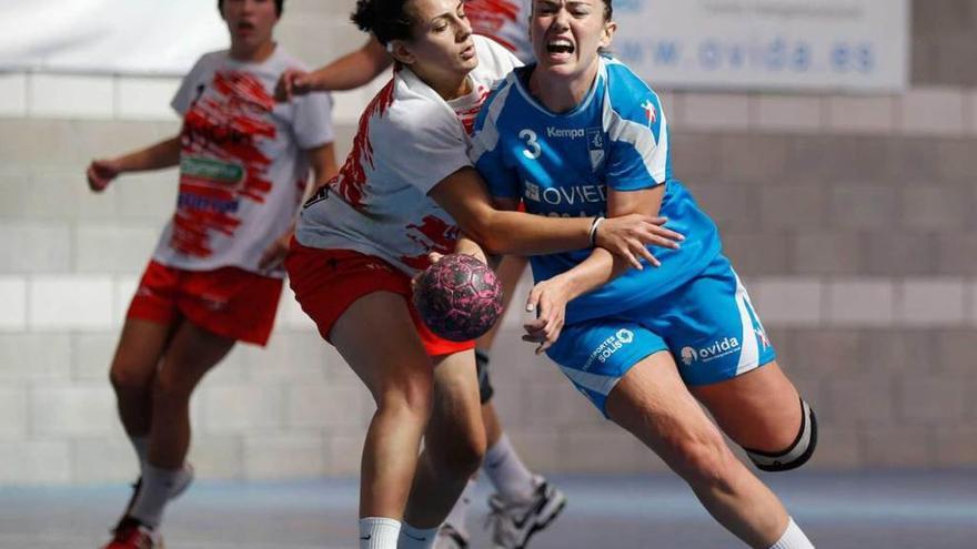 Vicky, con el balón, defendida por una jugadora del Gijón Balonmano durante el toreno de San Mateo.