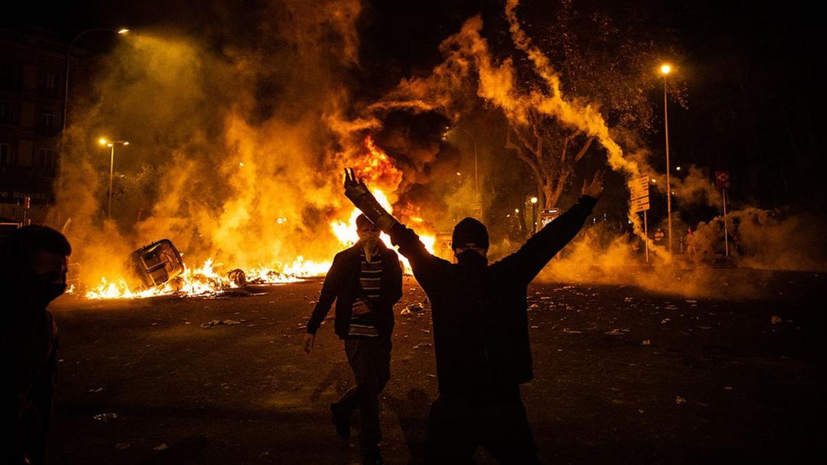 Un manifestante levanta los brazos junto a una hoguera durante la sexta noche de disturbios en Barcelona, este sábado en la plaza de Urquinaona