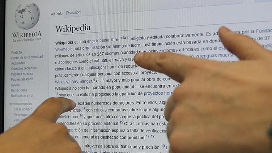 Dos usuarias consultan la enciclopedia digital Wikipedia.