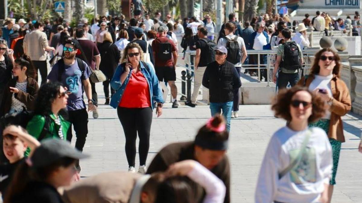 Multitud de persones passegen per la façana marítima de Sitges el Divendres Sant
