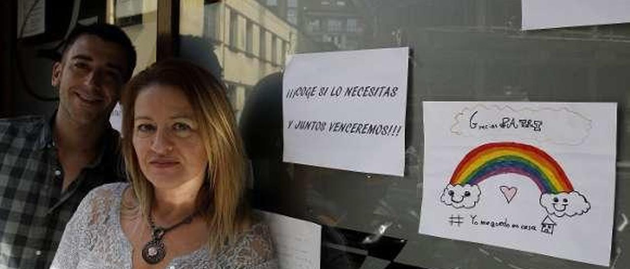 Patricia Fernández y Mario Rico, en su bar, El Olivo, con los carteles de agradecimiento de sus vecinos.