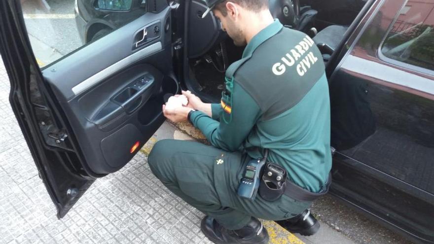 Un guardia civil durante el registro y las 500 dosis de cocaína que se hallaron ocultas en el vehículo