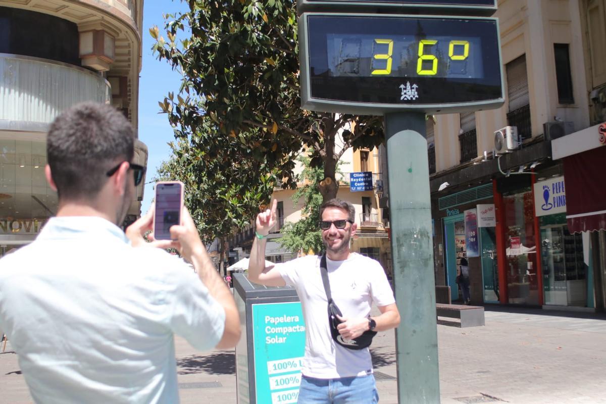 Un joven se fotografía ante un termómetro urbano en la calle Cruz Conde, que marca una temperatura de 36º, inusual para un mes de abril.
