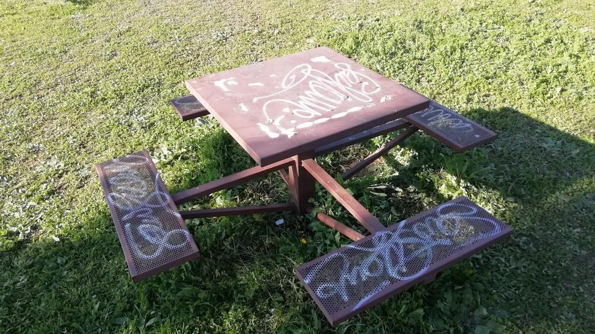 Las pintadas han dañado el banco y mesa de una zona de ocio y descanso.