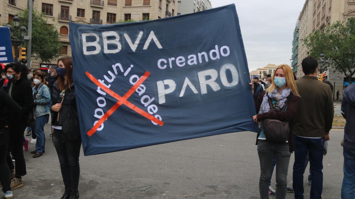 Pla obert de dues treballadores del BBVA aguantant una pancarta de protesta contra l'ERO plantejat per l'entitat. Imatge del 25 de maig de 2021. (Horitzontal)