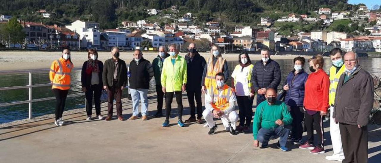 Los participantes hacen un alto en el camino para posar en una foto con la playa de Banda do Río, en Bueu.  | // FDV