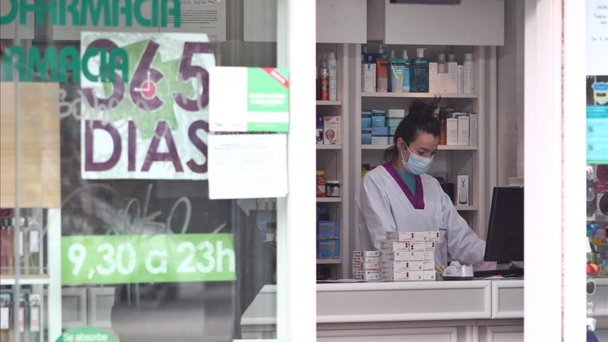 Una empleada de una farmacia de Madrid trabaja con mascarilla