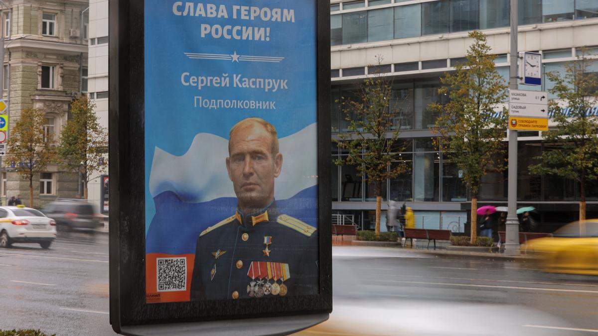 Cars drive next a board with an image of a Russian service member in Moscow