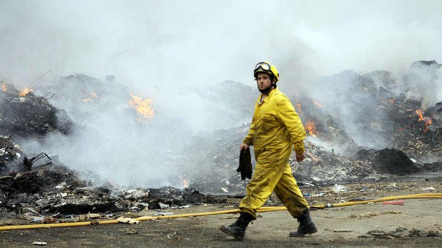 Un operario pasea frente al incendio declarado en el vertedero.